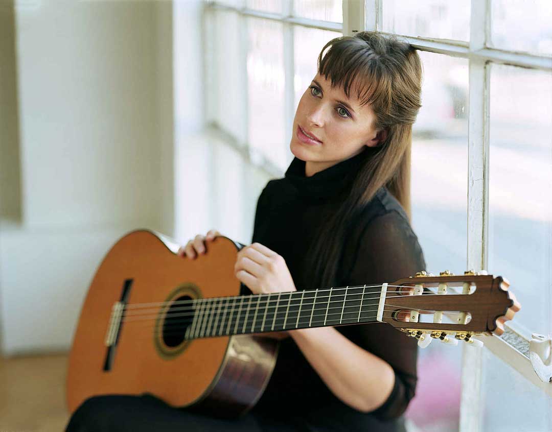 Martha Masters with a guitar in a window